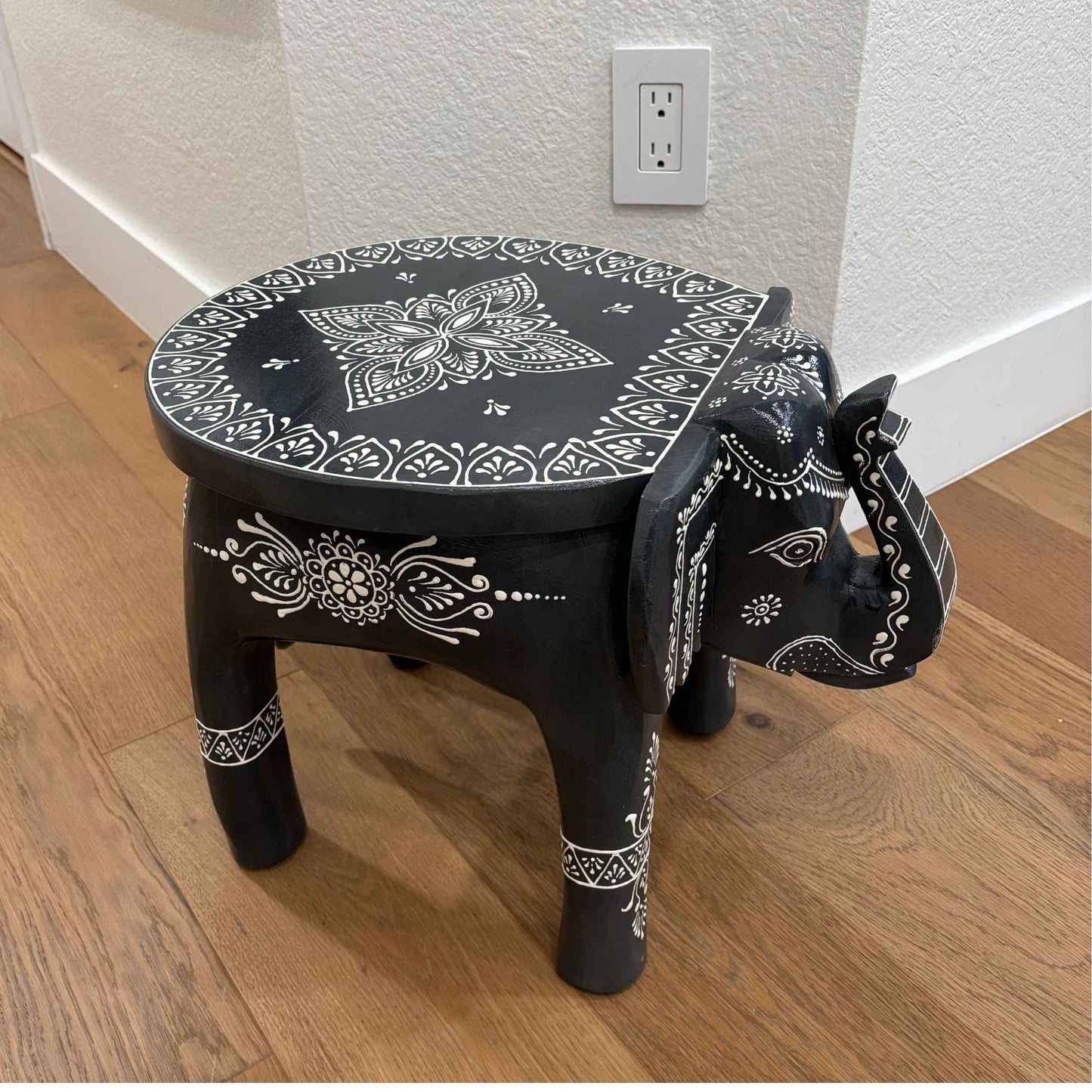 Close-up of intricately carved elephant legs supporting the boho-style wooden side table
