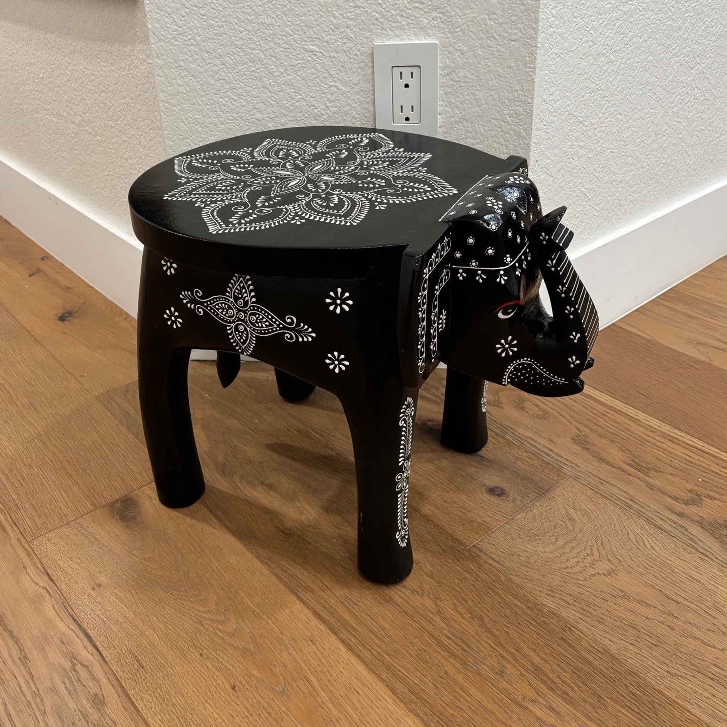 Side angle of the handcrafted wooden elephant stool with detailed carvings and sturdy legs