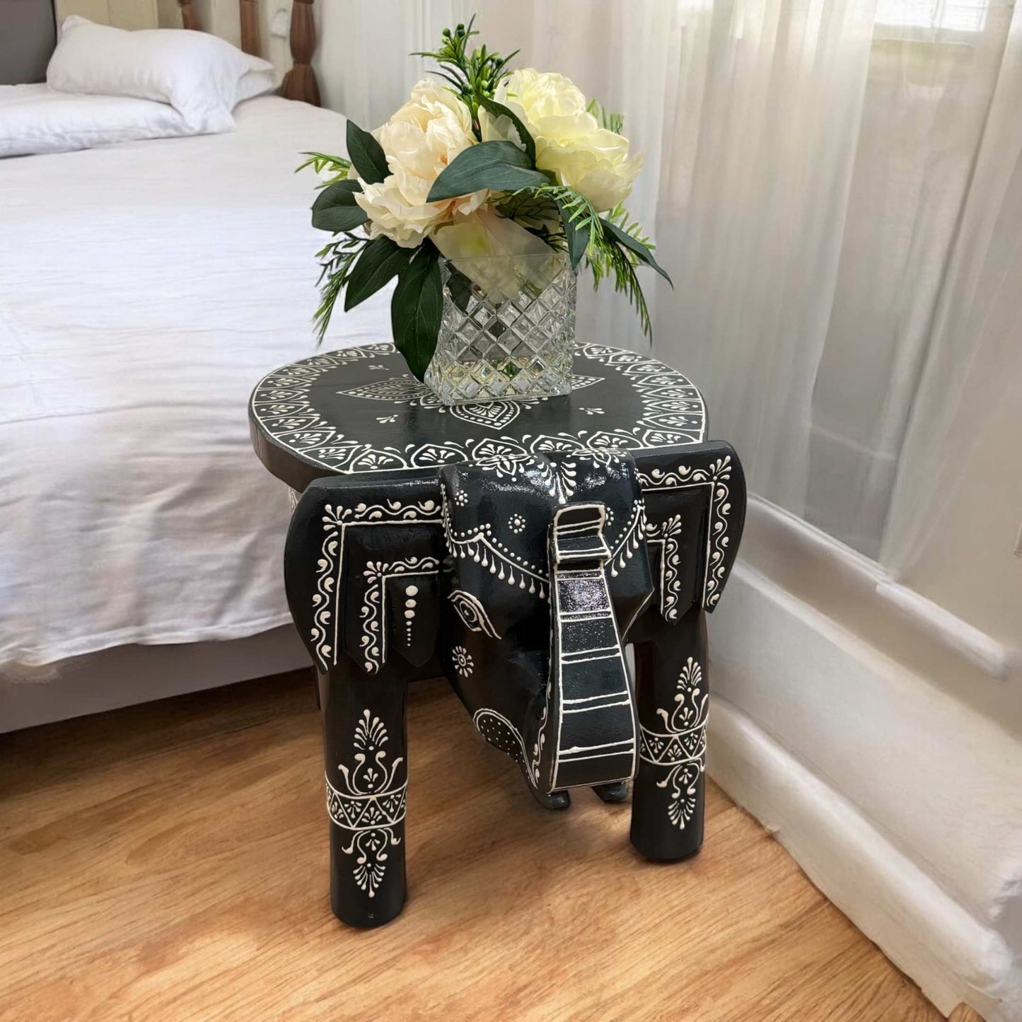 Black elephant stool displayed as a stylish accent table in a modern bedroom room setting