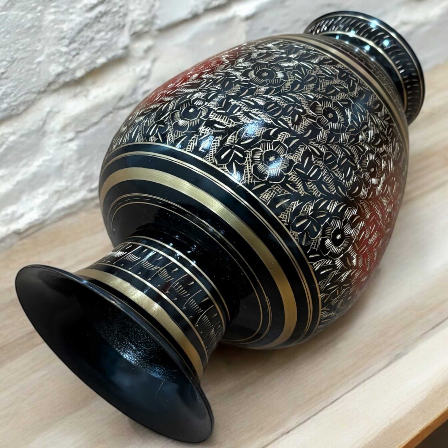 Side view of black brass vase, highlighting its curved shape and artistic floral detailing