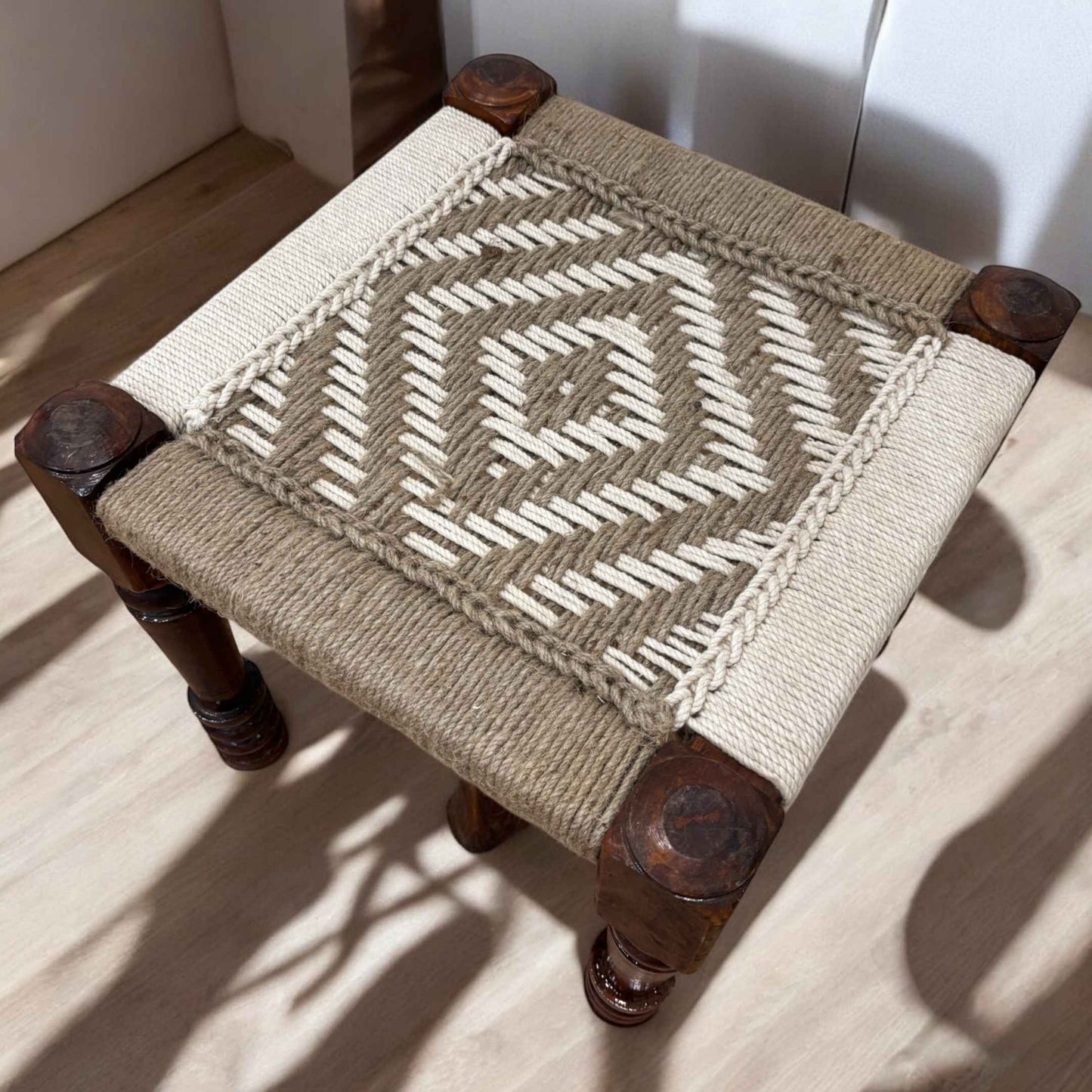 Handcrafted Charpai stool with intricately woven jute cord top, showcasing a clean and organic aesthetic.