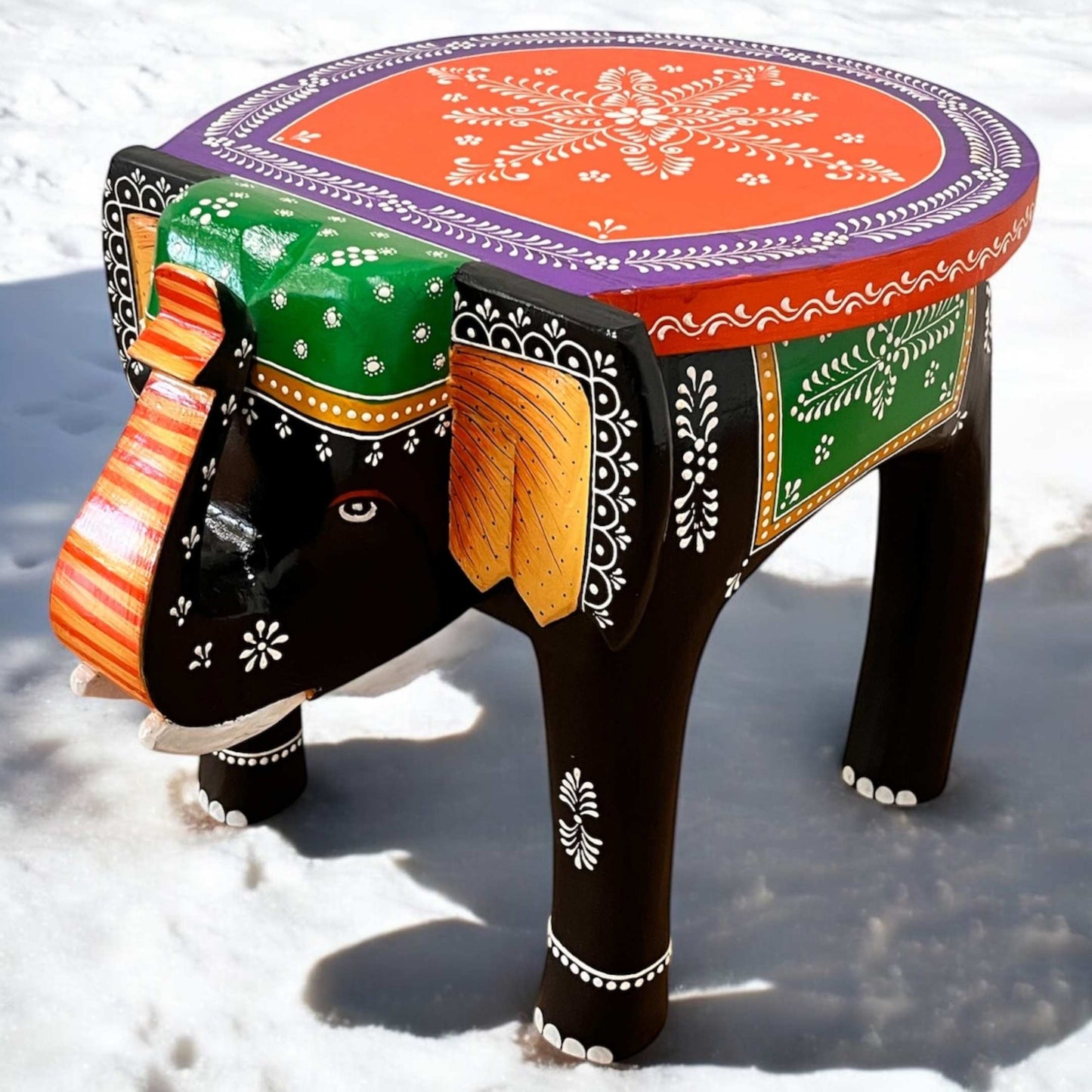 Close-up of intricately carved black orange elephant legs supporting the boho-style wooden side table