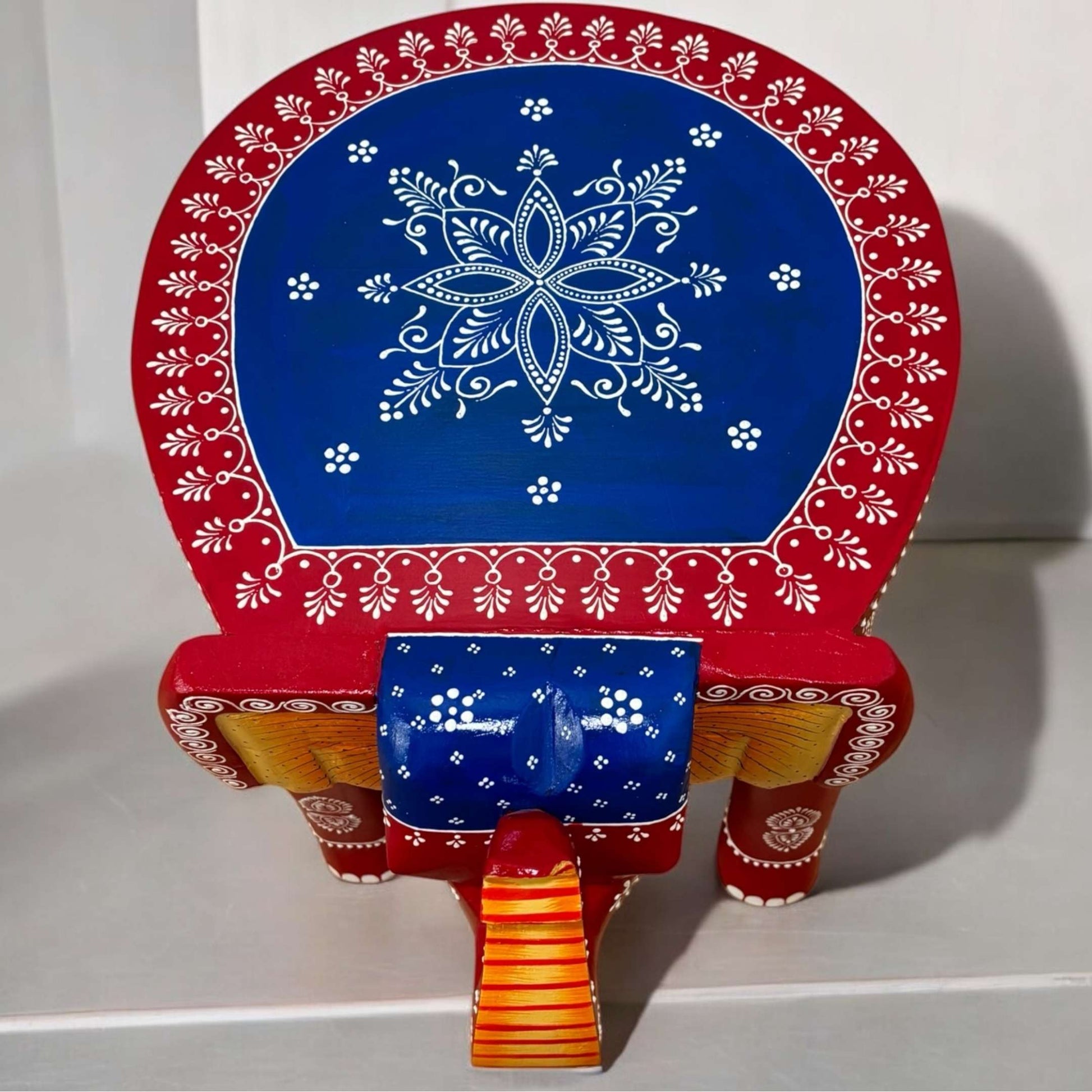 Top view of the wooden elephant stool showcasing its smooth round tabletop and colorful finish