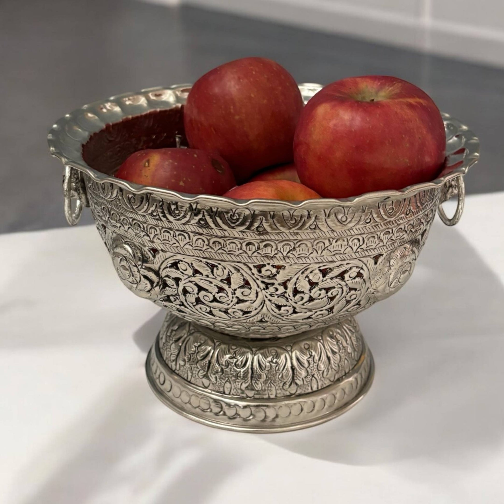 The antique silver fruit bowl filled with an assortment of colorful fruits, highlighting its functionality and aesthetic appeal as a centerpiece