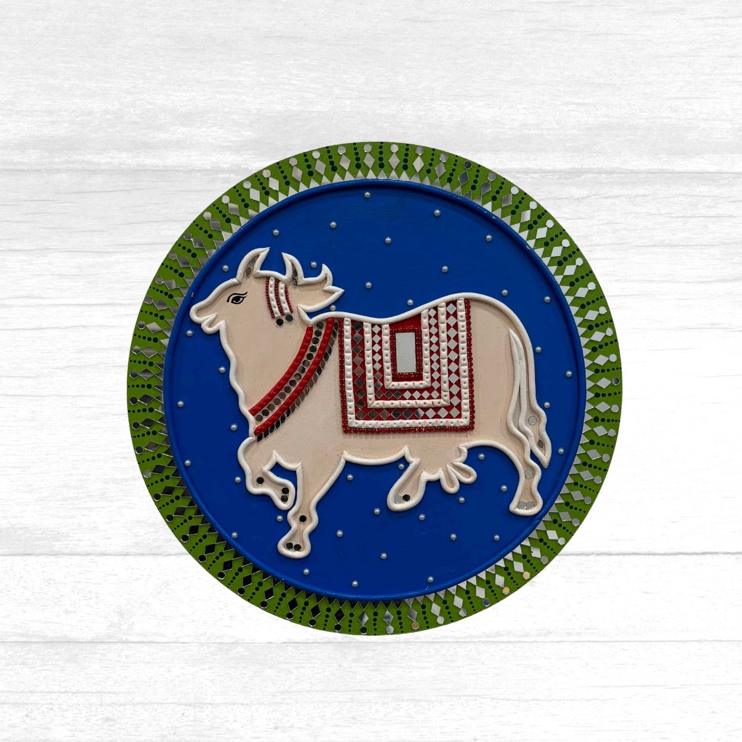 Handcrafted 12-inch Kamdhenu Lippan wall art featuring traditional Pichwai cow motifs with intricate mud and mirror work.