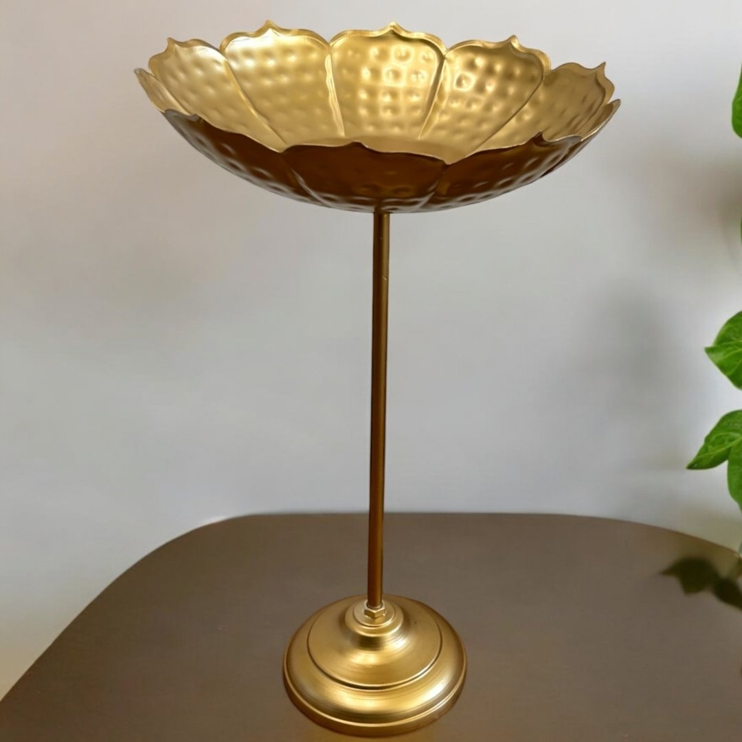 Single standing lotus bowl photographed against neutral background with plants, showing full stem height and base along with bowl’s fluted design.