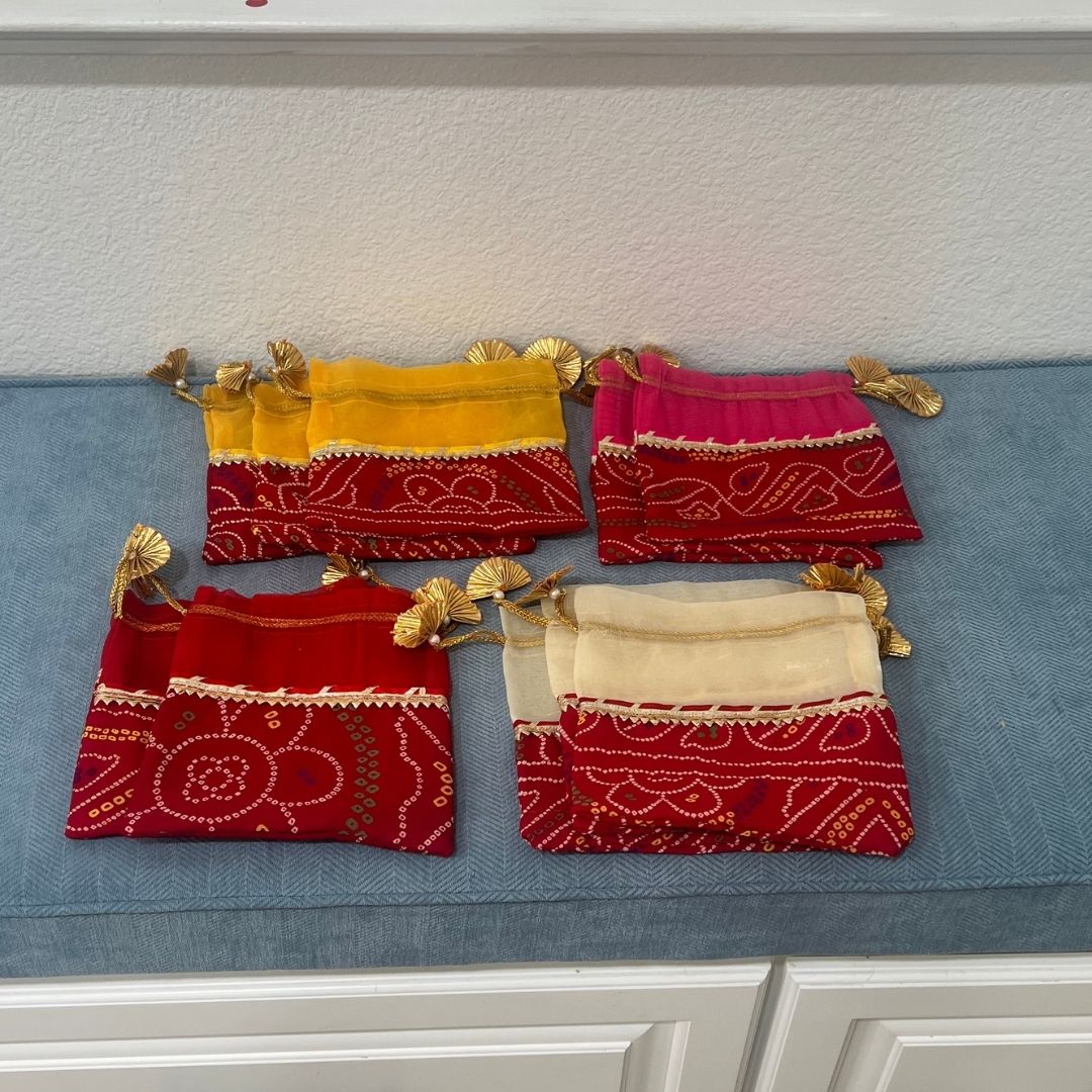 Set of red, yellow, and pink fabric pouches with gold accents on a blue surface.