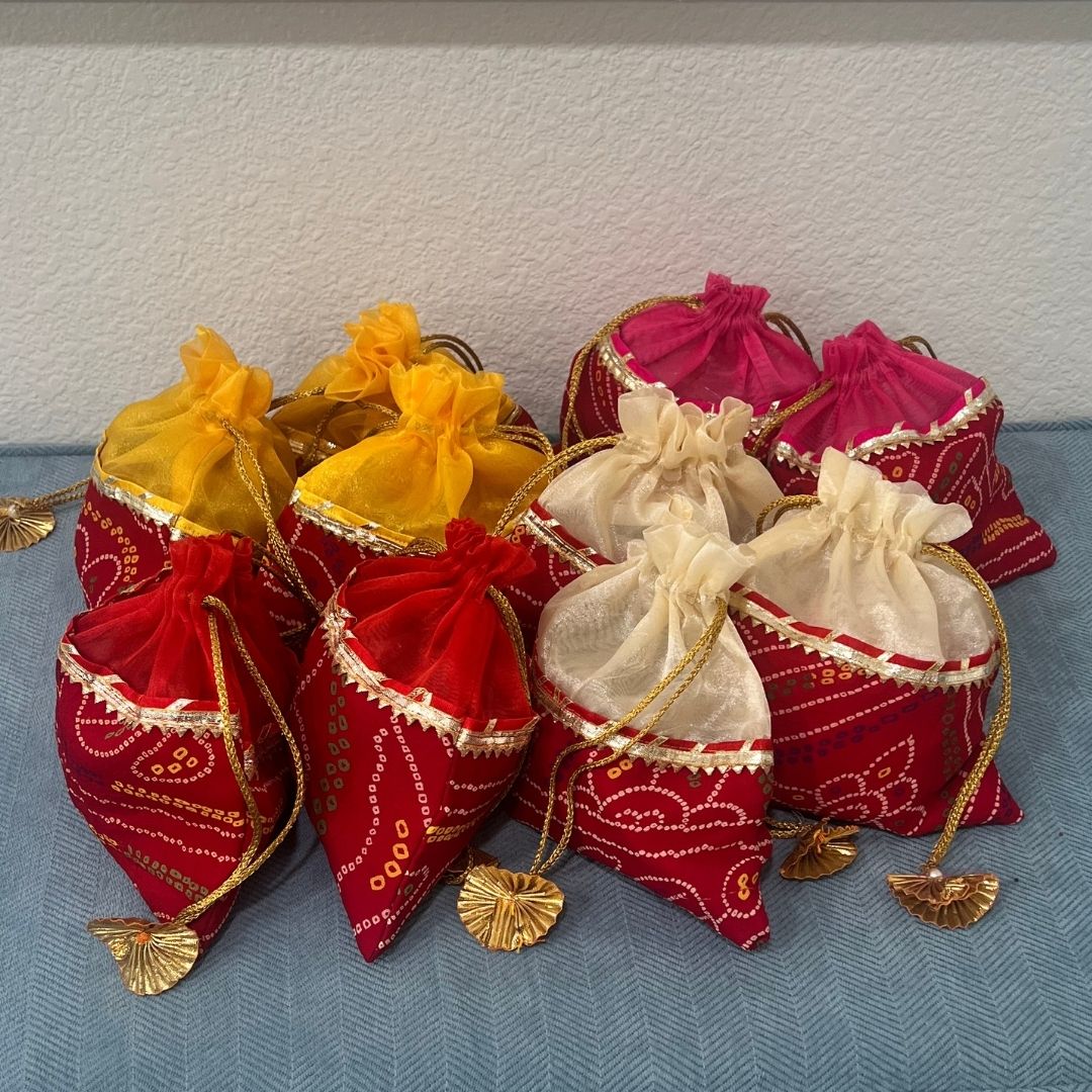 Decorative bags in red, yellow, and white with gold accents on a textured surface.