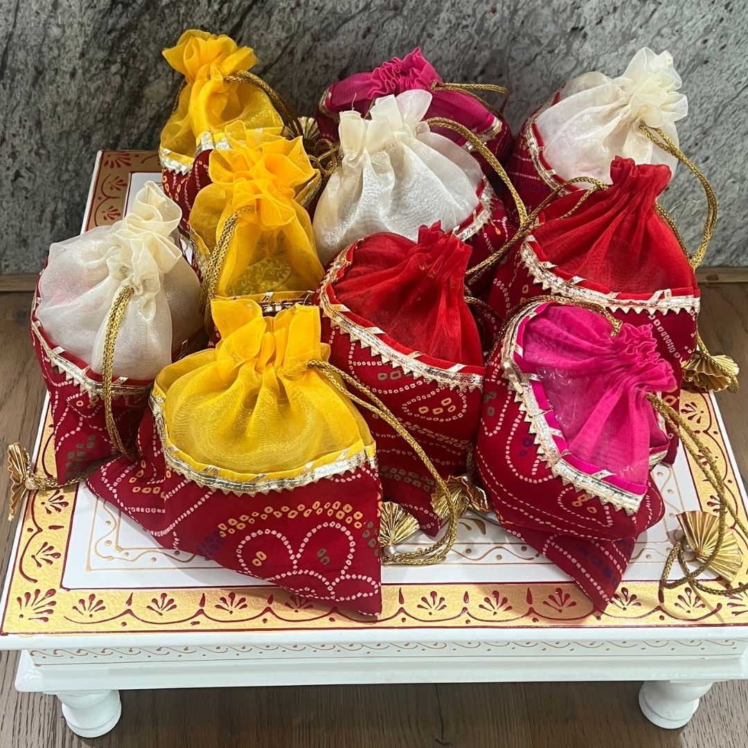 Decorative bags in red, yellow, and white on a decorative tray with a stone wall background.