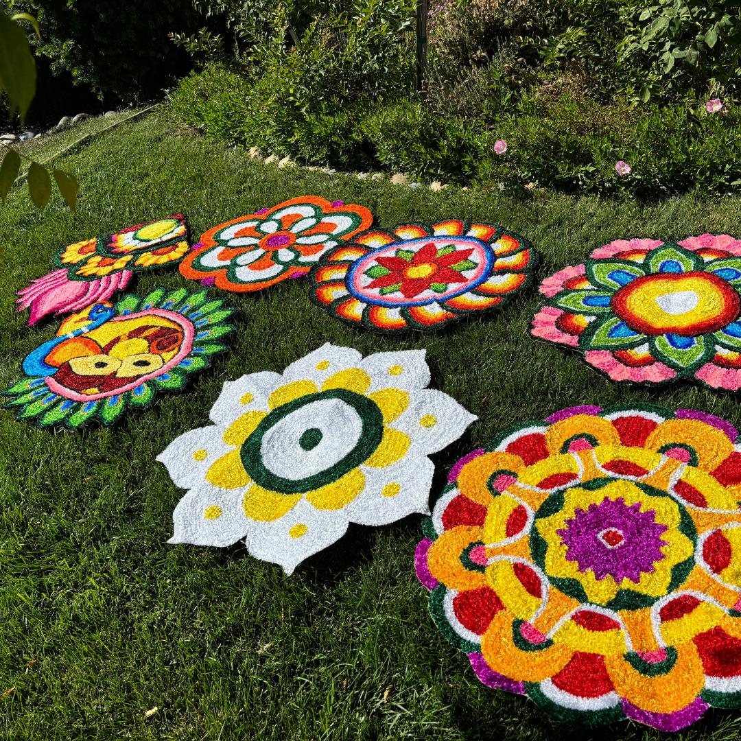 Seven round 3 ft rangoli mats laid out on grass, each with bright, multicolored floral and geometric designs for festive pooja decor