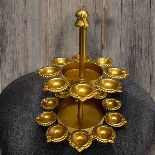 Urli Utsav Decor two‑layer gold finish diya urli displayed on dark stone surface, showing 18 unlit candle holders arranged in two concentric tiers with central hanging hook