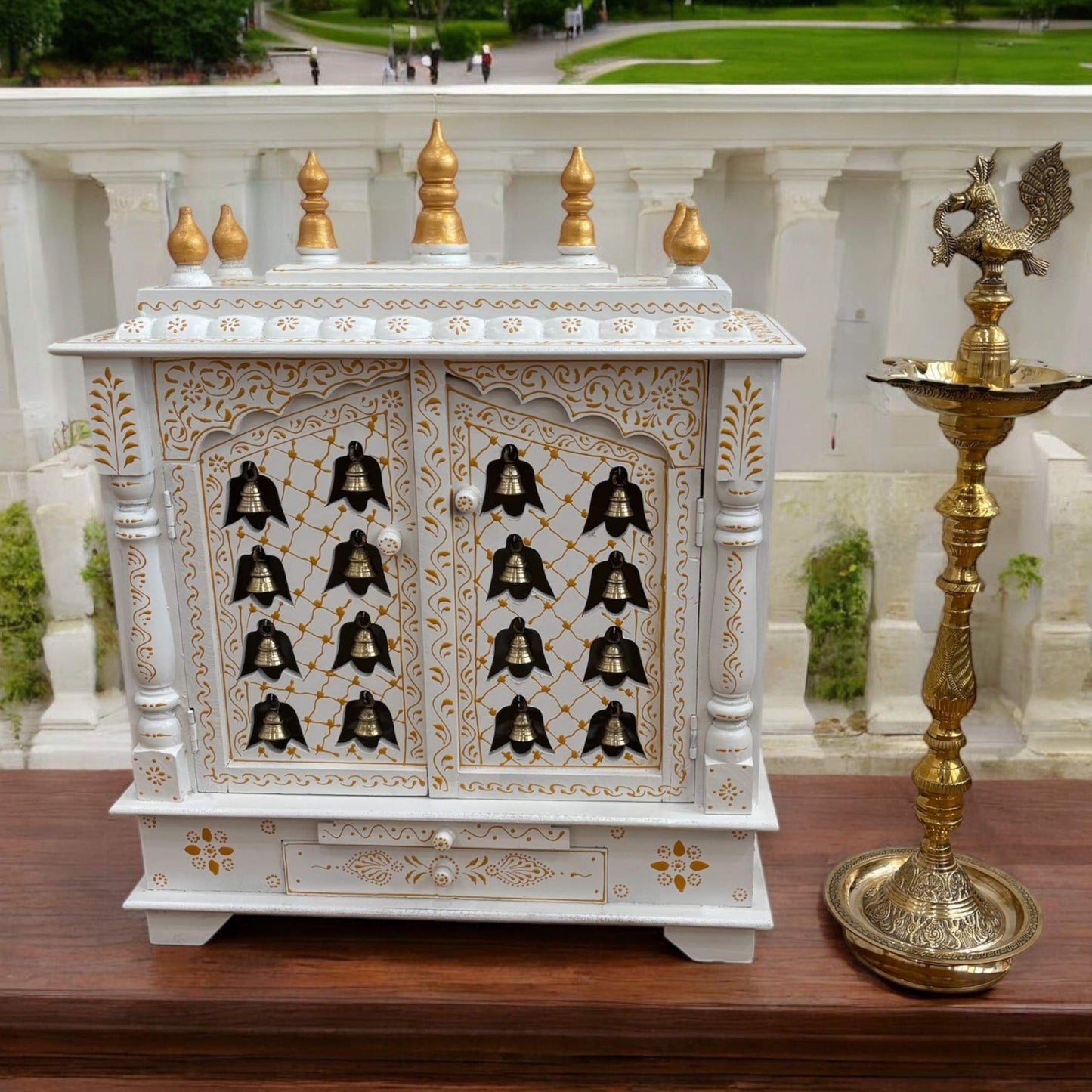 Front view of the handcrafted white and gold wooden temple with intricate carvings and brass hanging bells