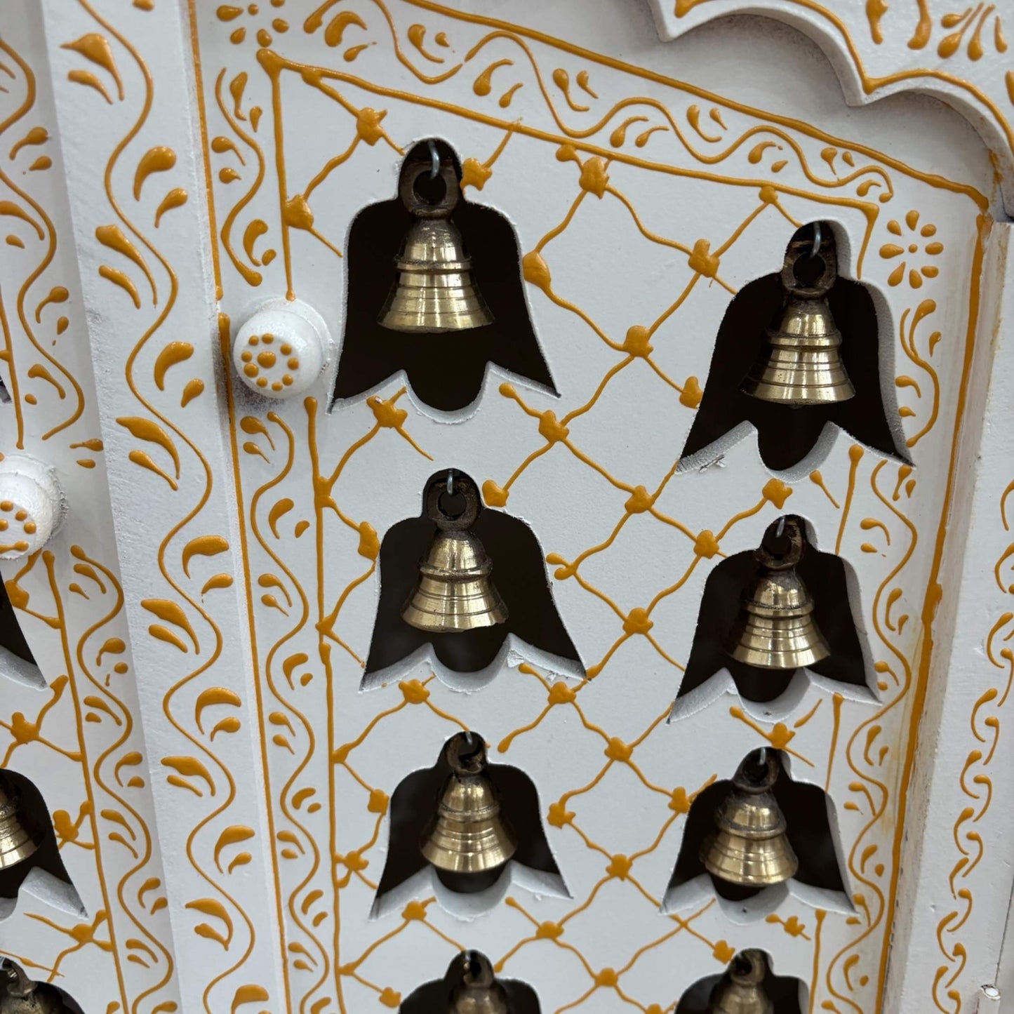 Front view of the handcrafted white and gold wooden temple with intricate carvings and brass hanging bells