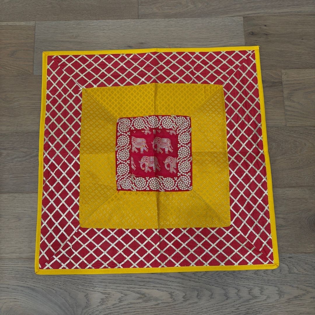 Decorative quilt with red and yellow pattern on a wooden floor