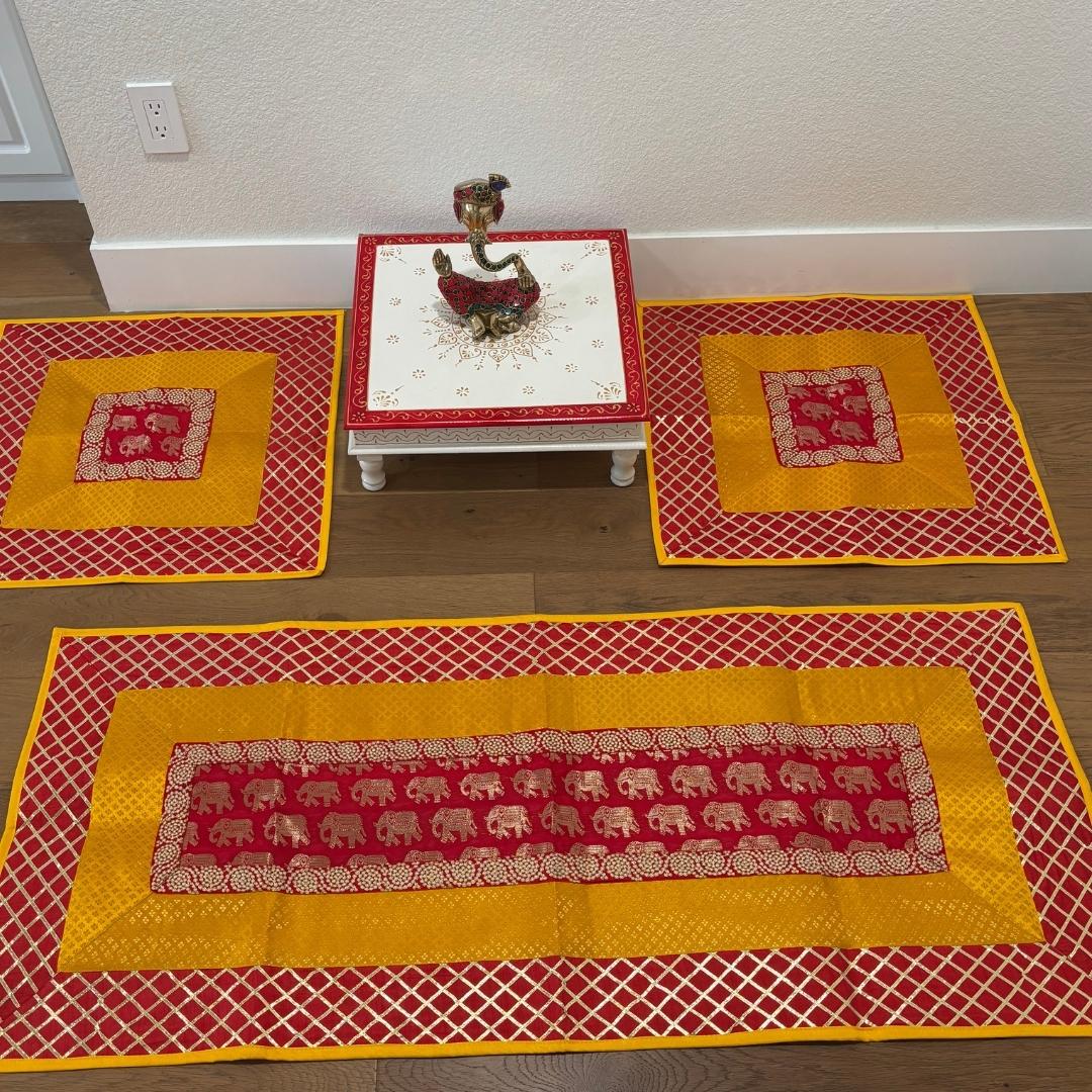 Red and yellow elephant motif silk brocade runner and mats displayed flat—vibrant pooja aasan set for Diwali and meditation.