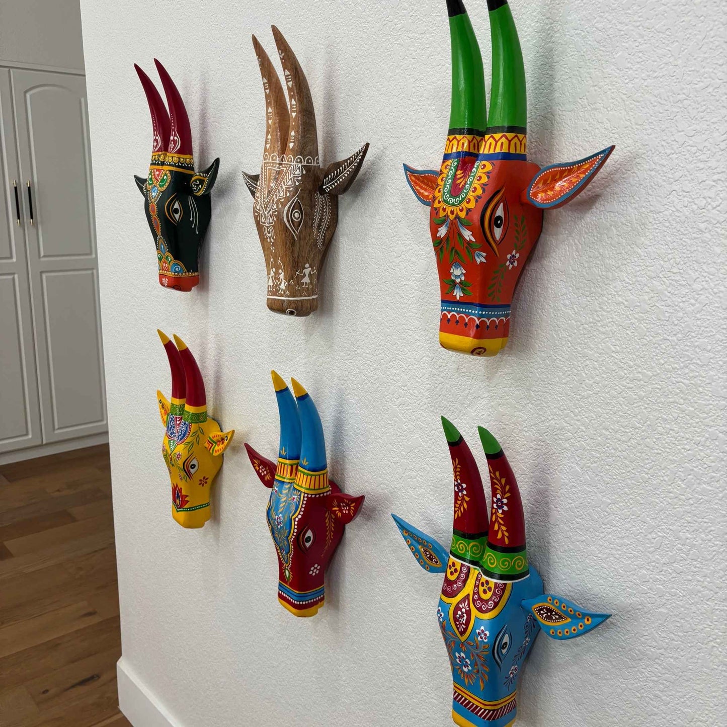 Close-up of Urli Utsav's handcrafted wooden cow head, highlighting detailed carvings and traditional hand-painted patterns.