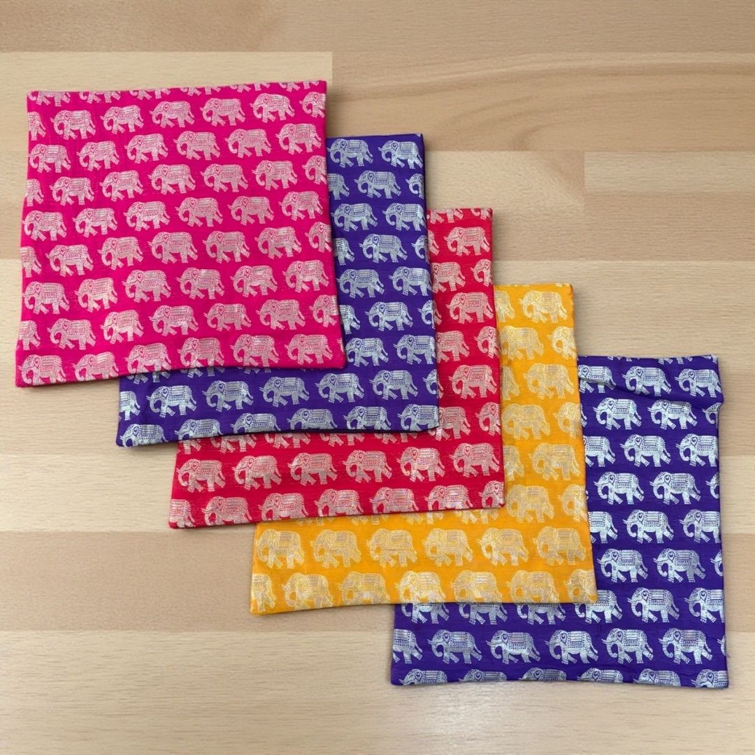 Set of colorful fabric panels with elephant patterns on a wooden surface