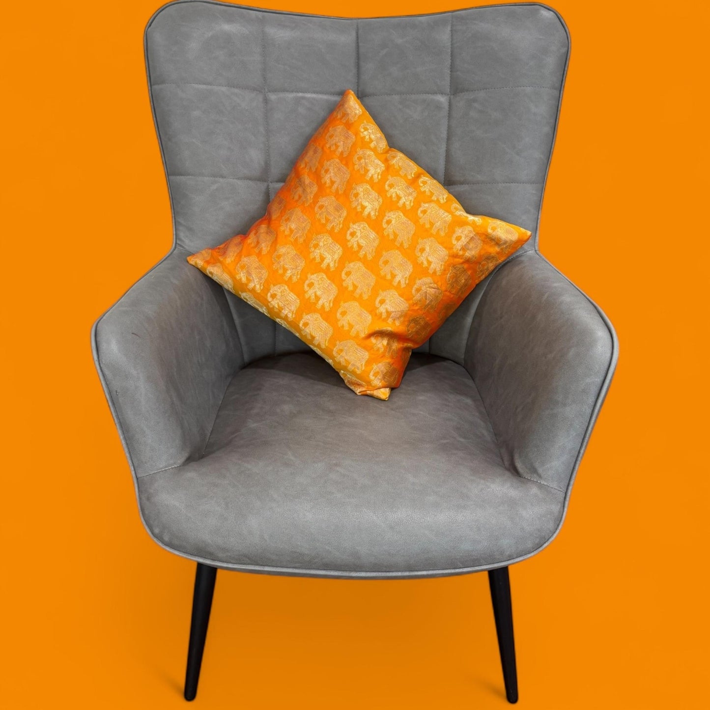 Gray chair with an orange pillow on an orange background