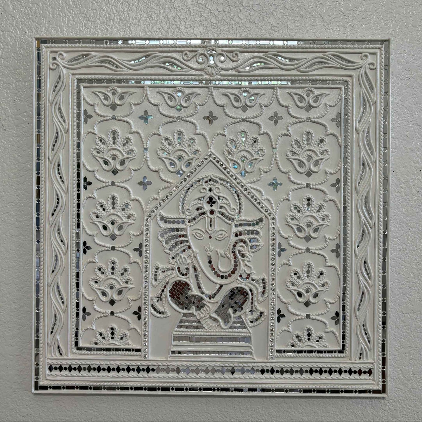 Decorative Ganesha Lippan wall art with intricate design on white wall