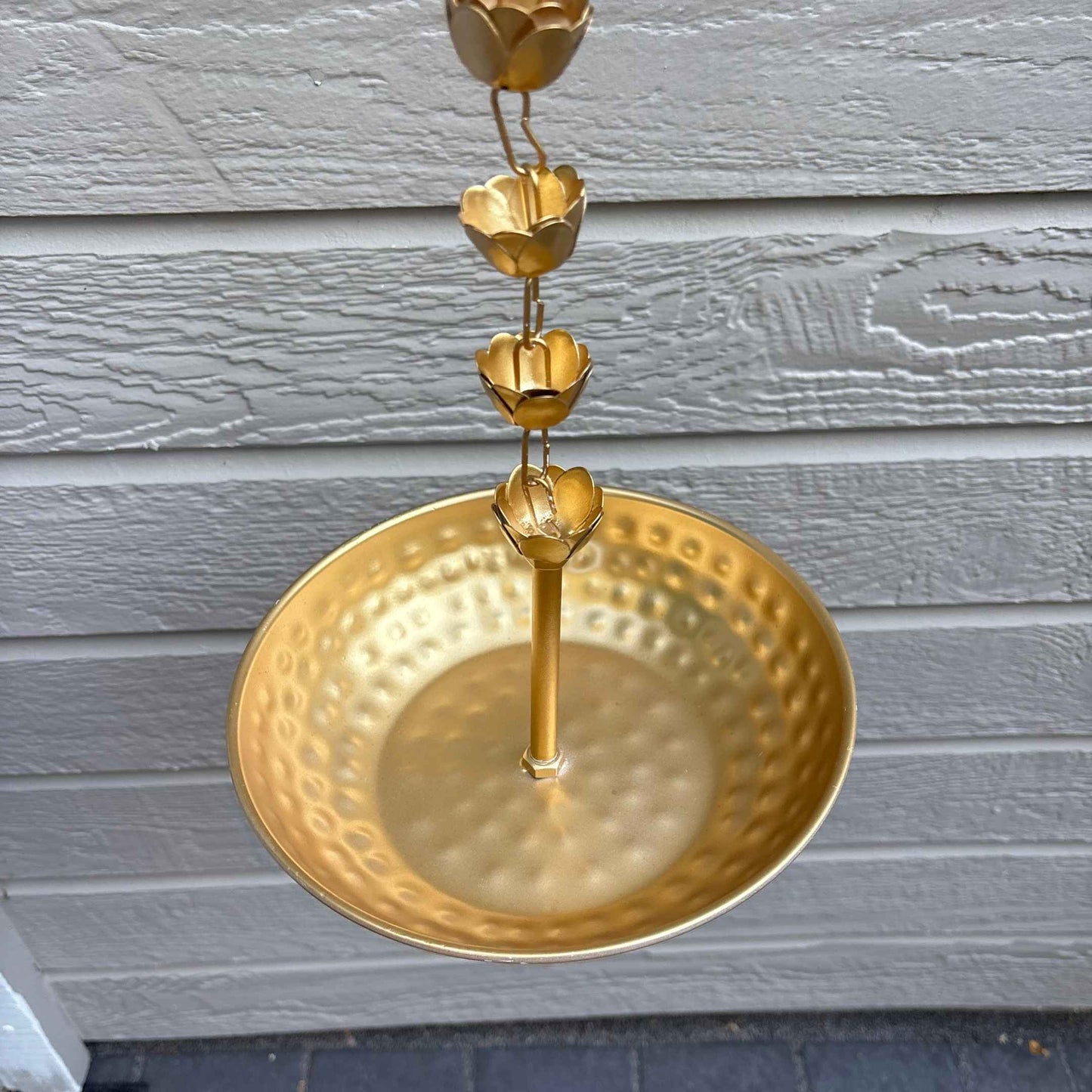 Closeup look of hammered hanging urli, Gold chain with decorative design on a gray wooden background