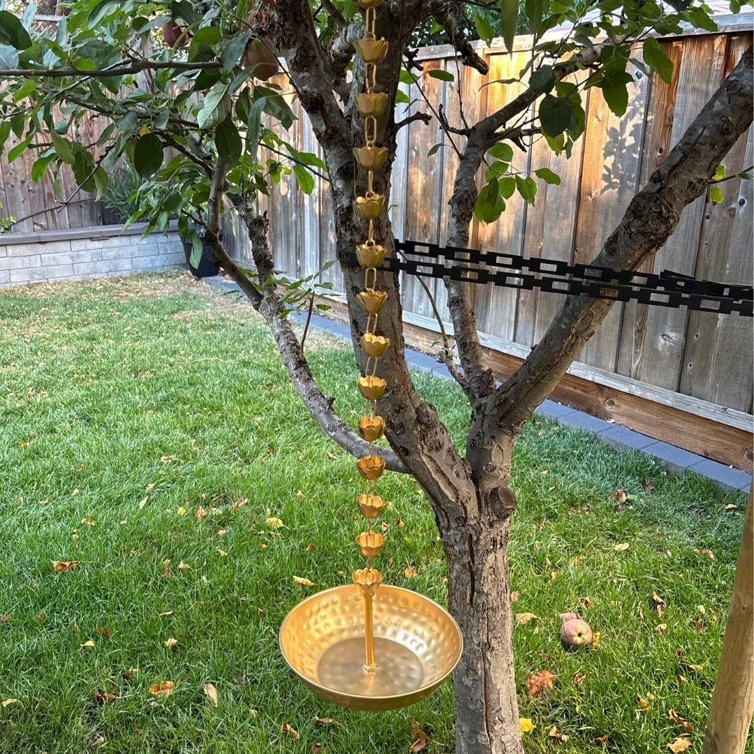 Gold hammered urli hanging from a tree in a backyard setting