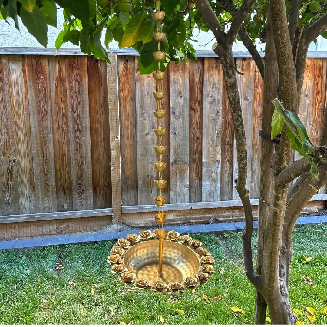 Gold rose hammered urli hanging from a tree in a backyard setting