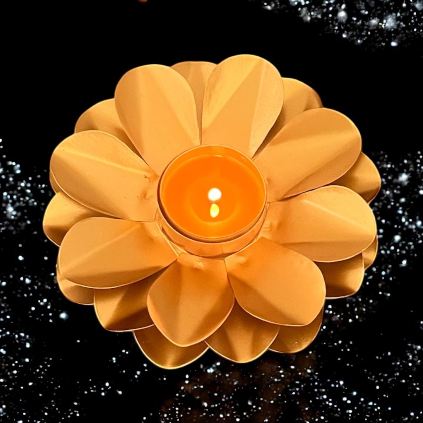 Flower-shaped candle holder with a lit candle on a black background