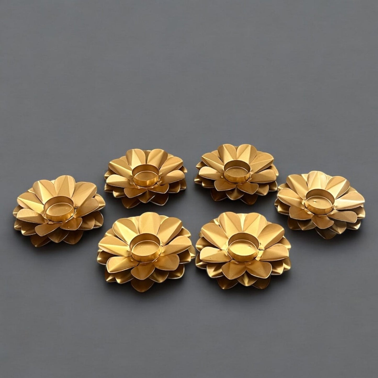 Set of six gold flower-shaped candle holders on a dark gray background