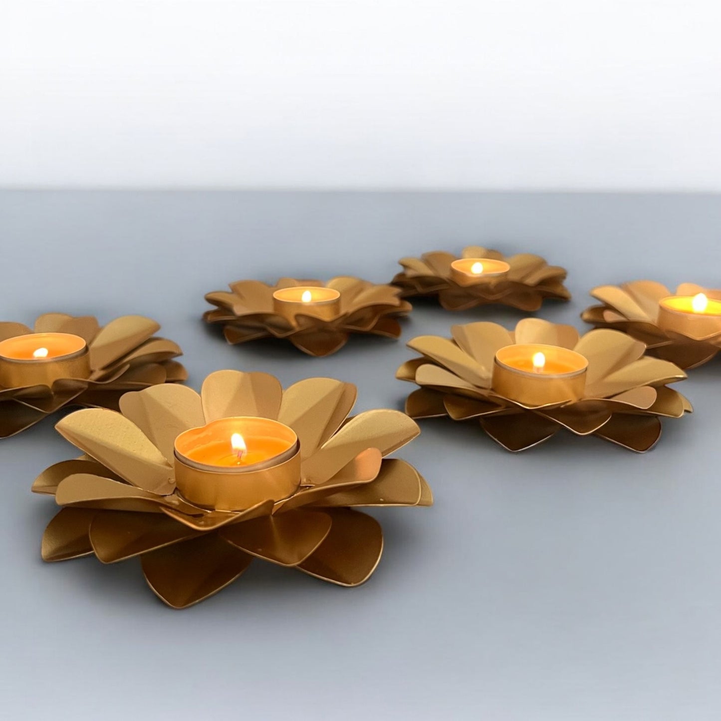Gold flower-shaped candle holders with candles on a light gray background