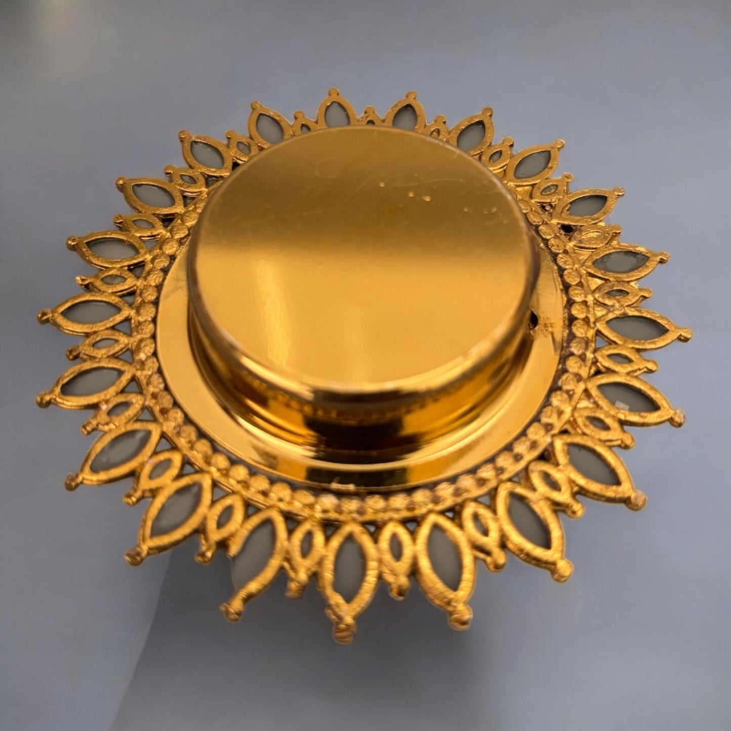 Gold decorative T-Light back view with intricate patterns on a gray background