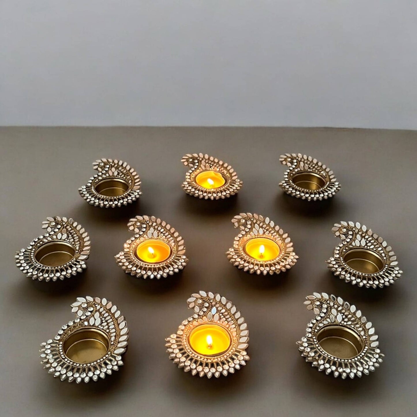 Mango paisley gold mirror Decorative candle holders with candles on a gray surface