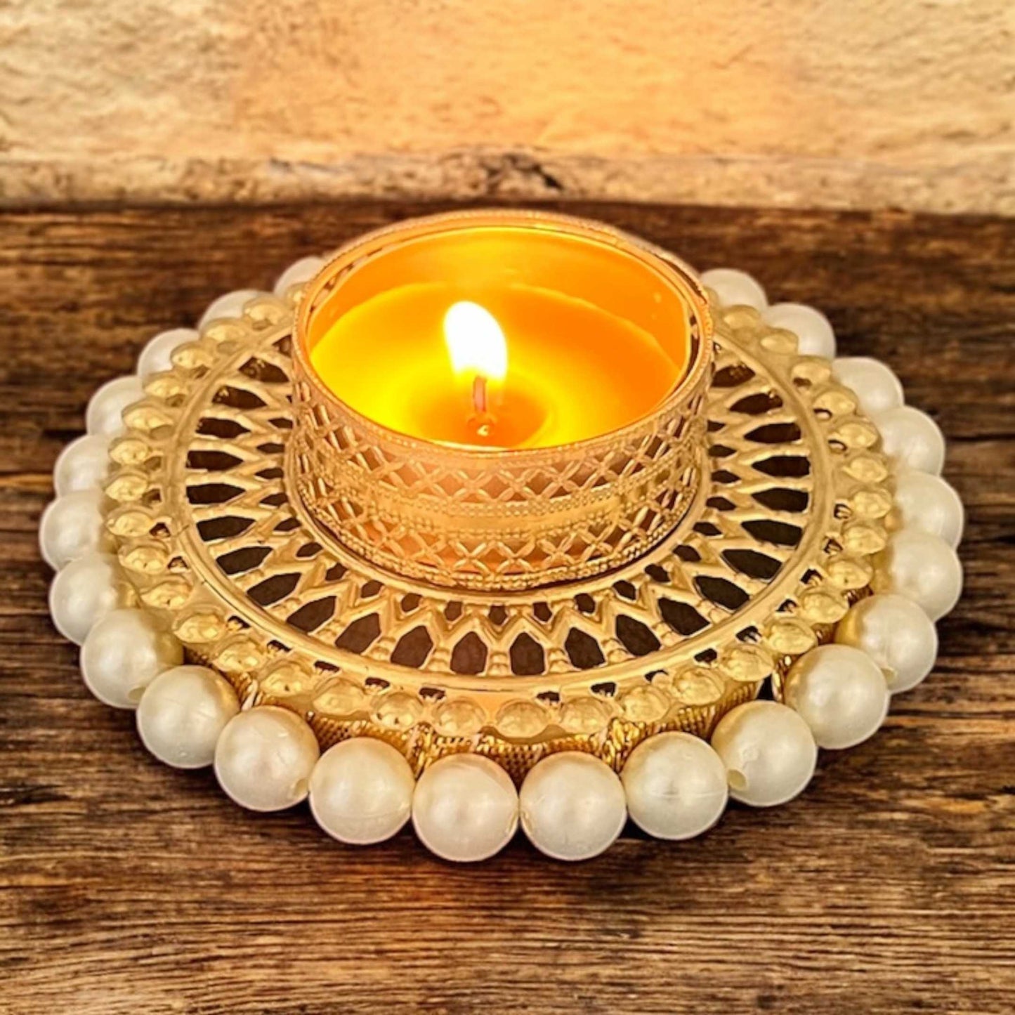 Decorative candle holder with a lit candle on a wooden surface