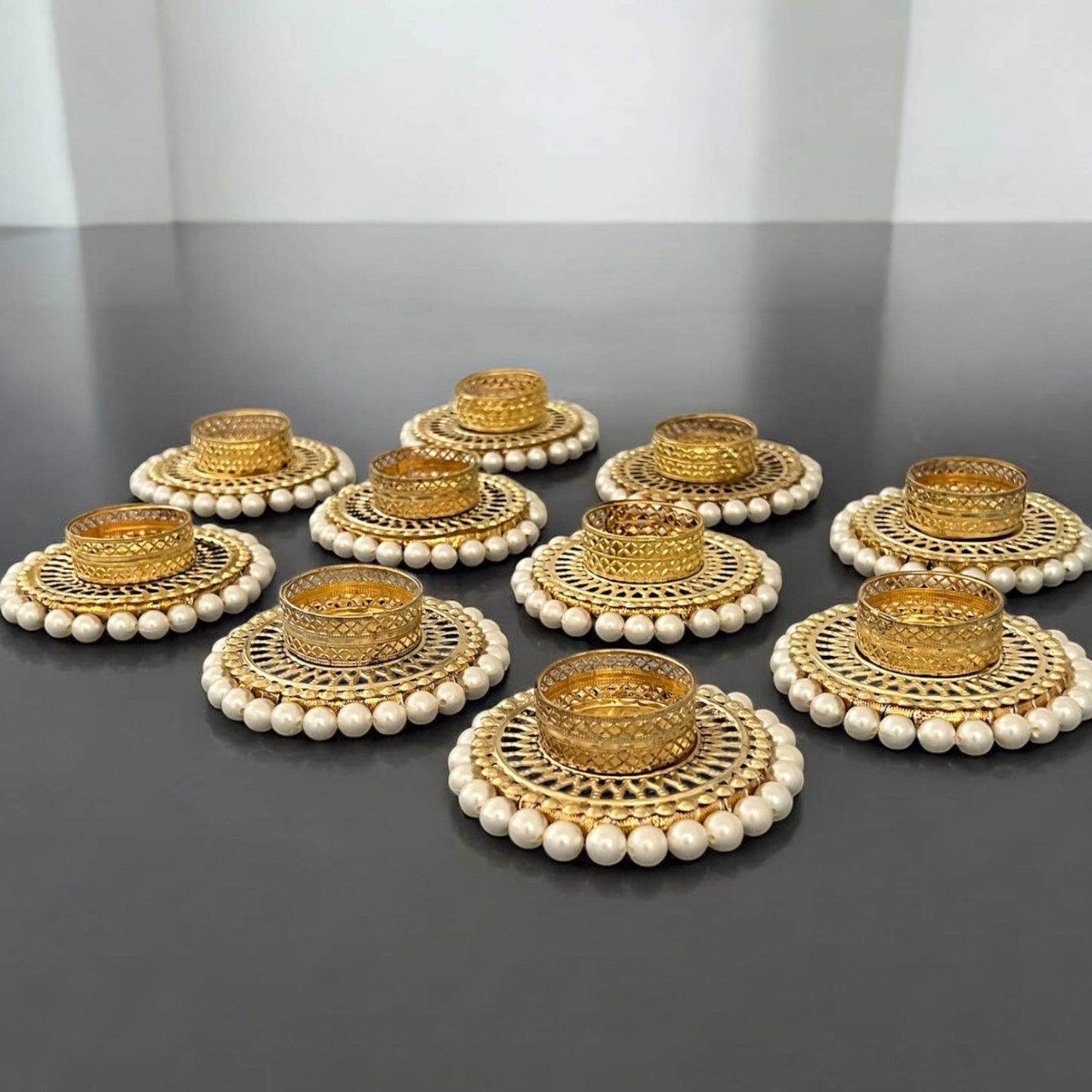 Set of gold and pearl tea lights on a dark surface