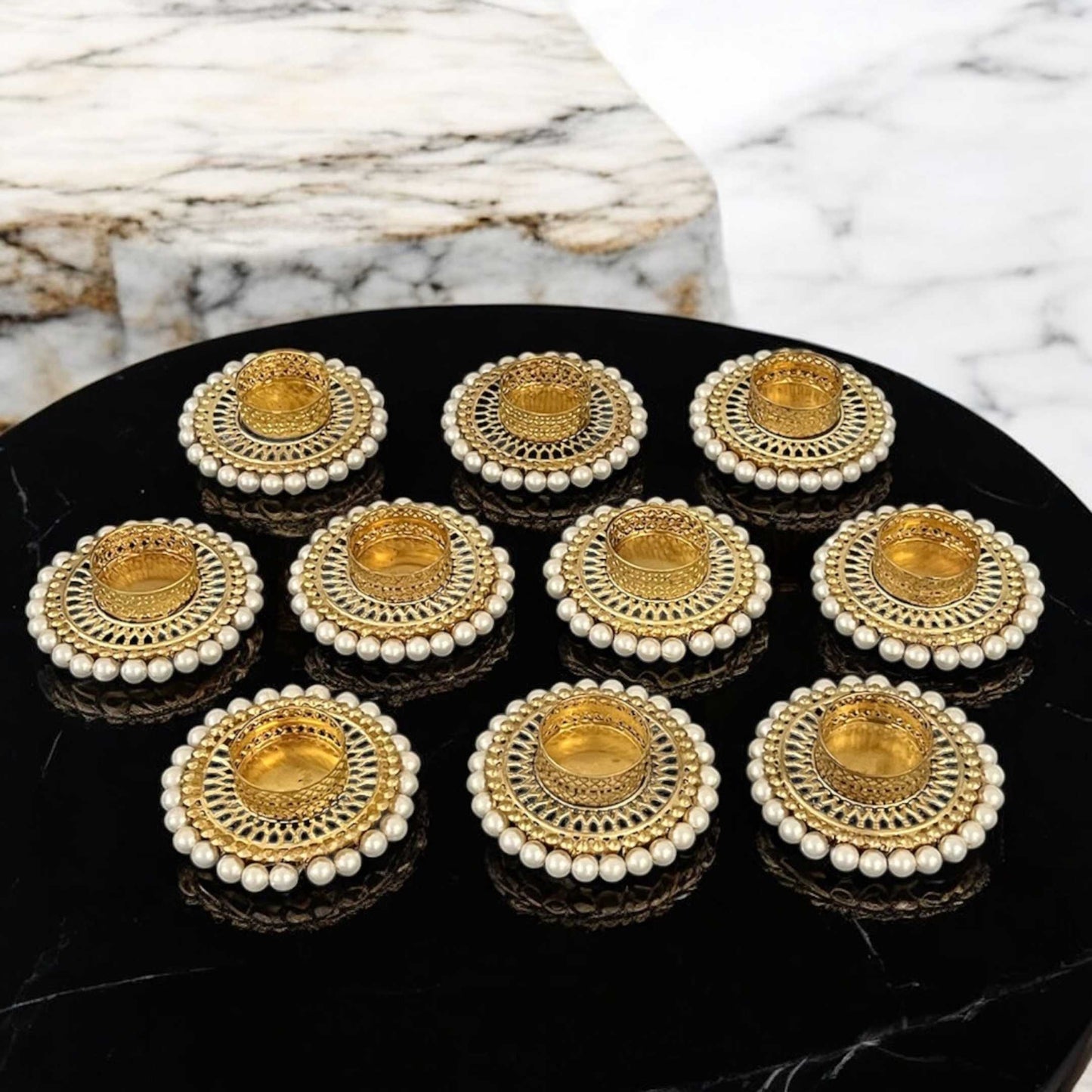Set of gold and pearl earrings on a black surface with marble background
