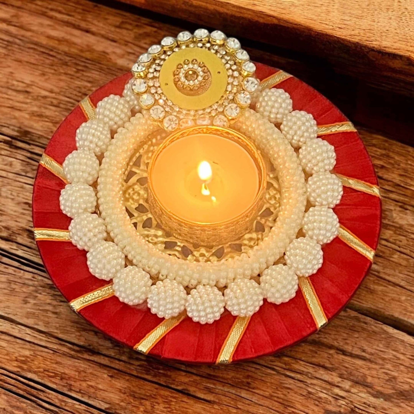 Decorative candle holder with pearls and gold accents on a wooden surface