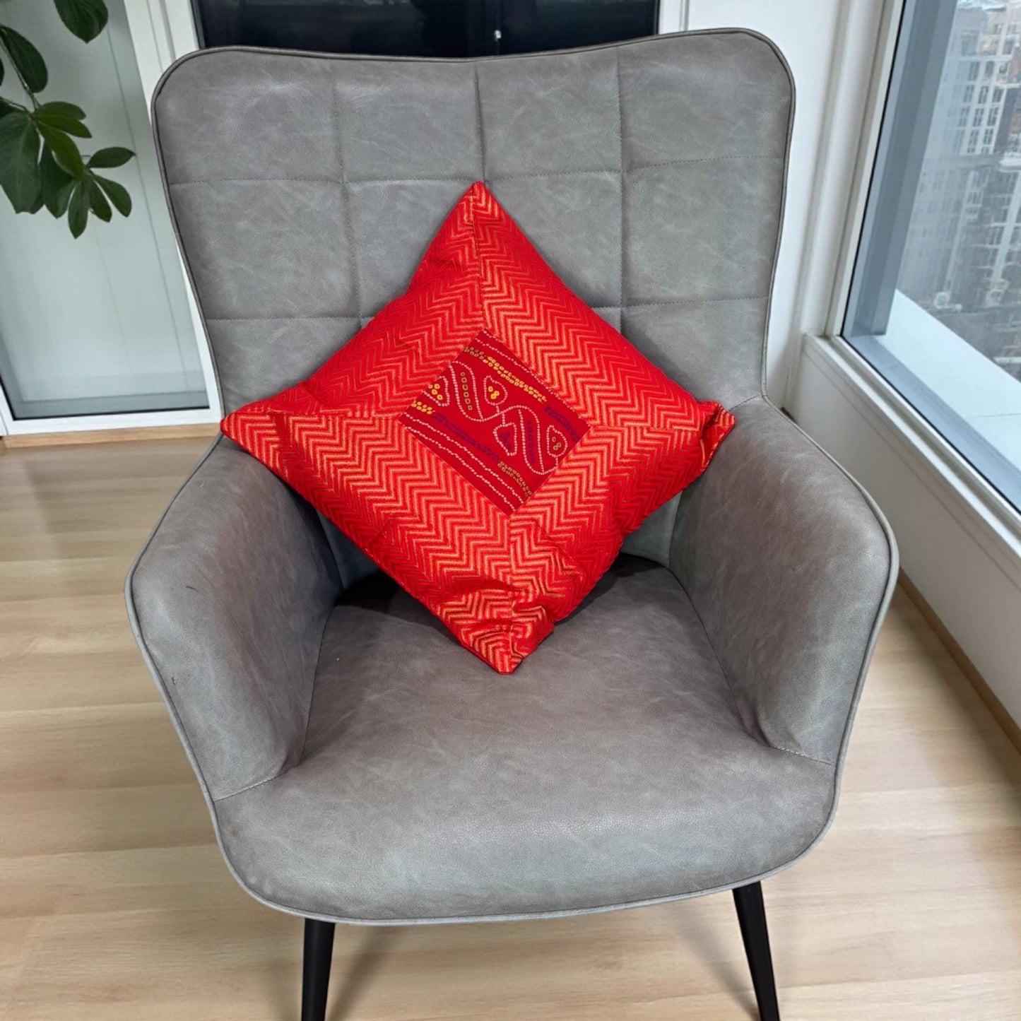 Single 16×16 red Bandhani silk brocade cushion cover on gray chair — handcrafted with hidden zipper