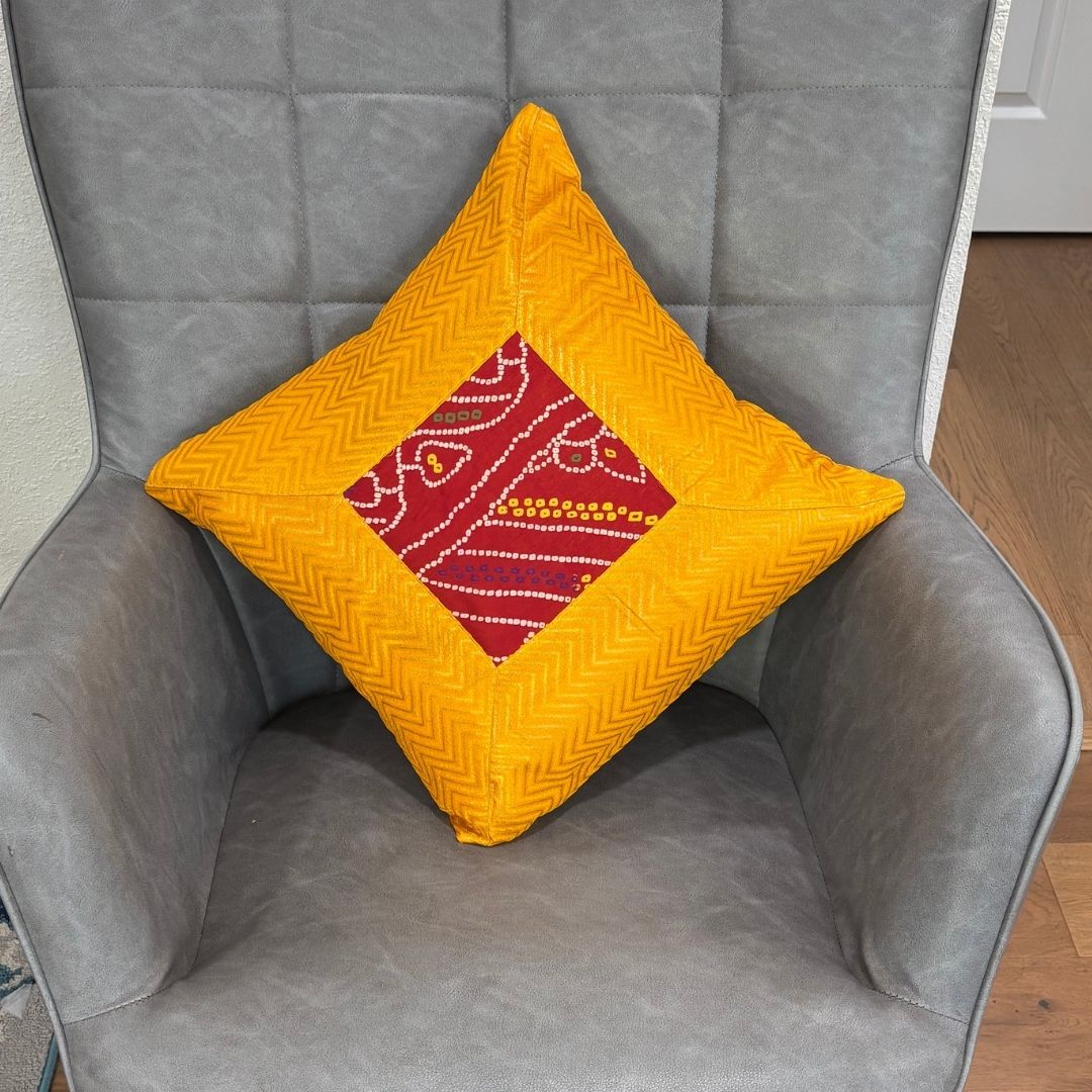 Yellow 16×16 Bandhani silk brocade cushion cover on chair — vibrant Diwali decor accent, handcrafted.