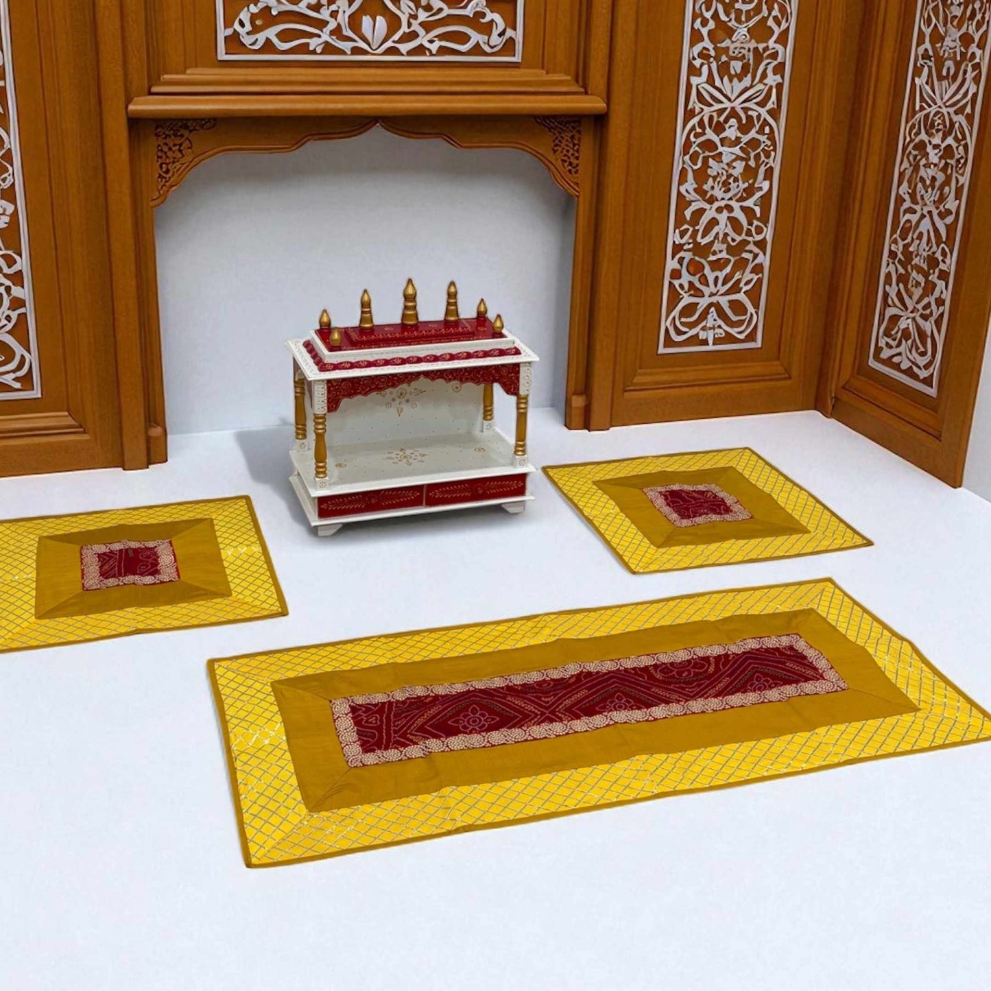 Decorative setup with a small table and three yellow mats with red patterns on a white background.