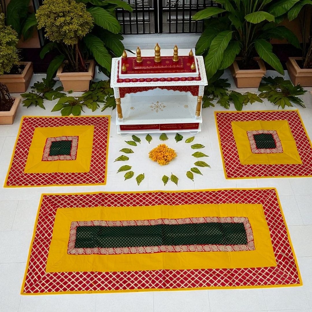 Decorative altar with yellow and red pooja aasan on a white floor, surrounded by potted plants.