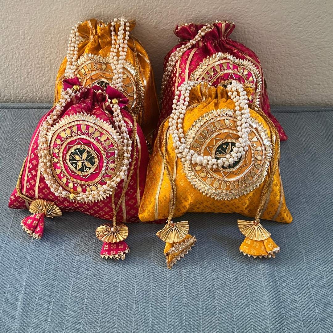 Decorative bags with intricate designs and pearl embellishments on a gray surface.
