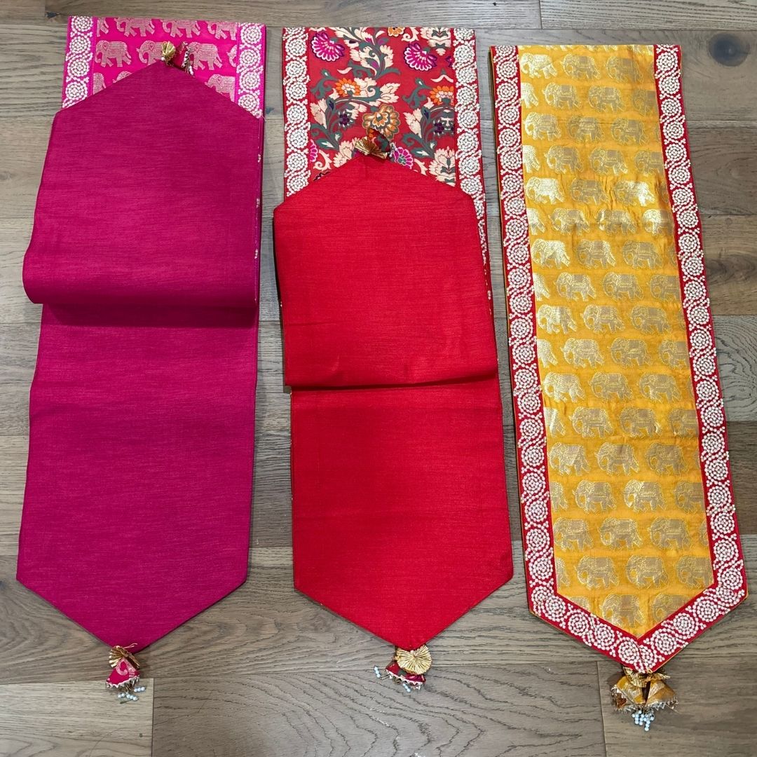 Three colorful table runners on a wooden surface