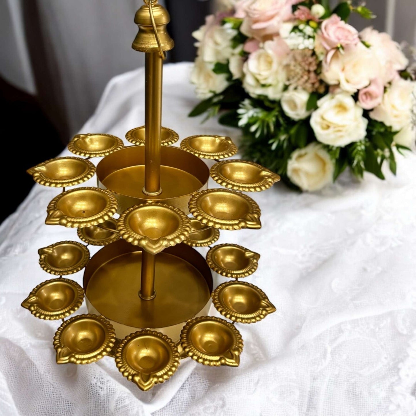 Gold decorative lamp with flowers in the background on a white tablecloth