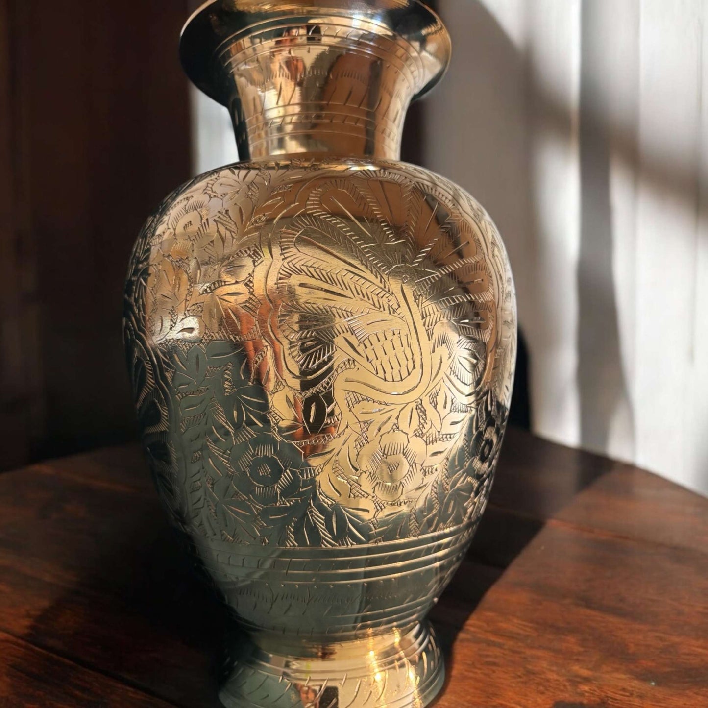 Brass vase illuminated by natural light, accentuating its golden sheen and engraved details.