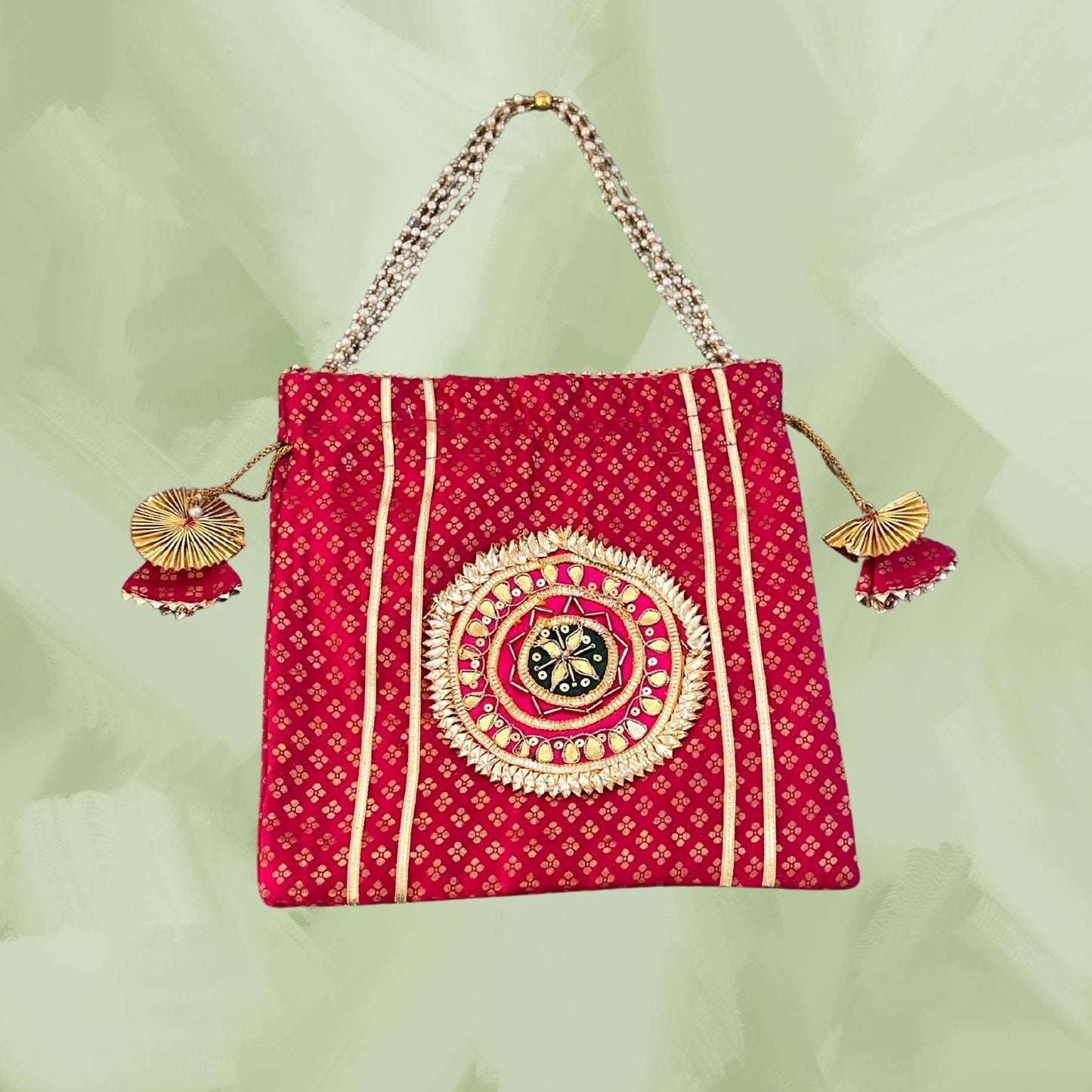 Red handbag with gold patterns and tassels on a light green background