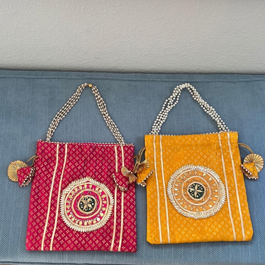 Two decorative handbags, one red and one yellow, with intricate patterns on a blue background.