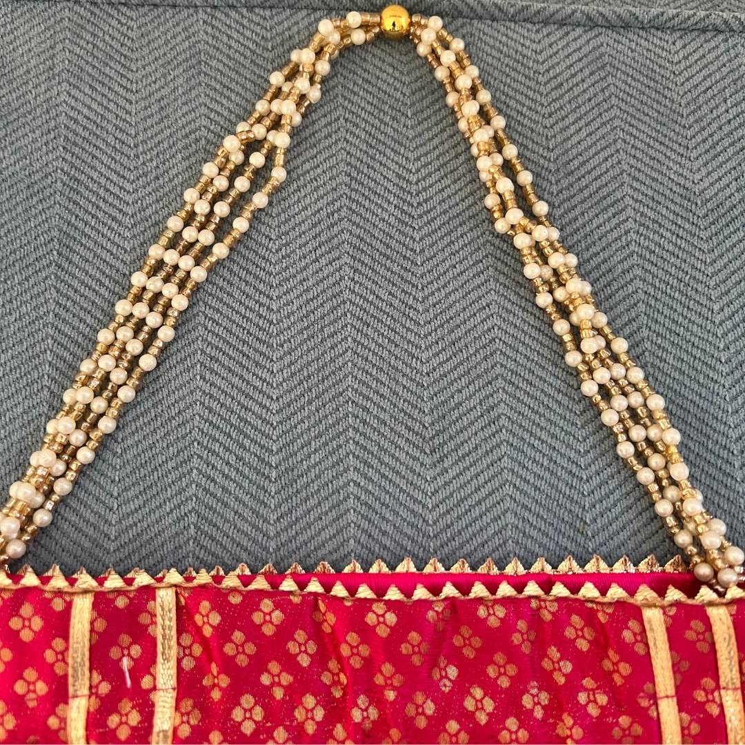 Red saree with gold border and a necklace on a gray textured background