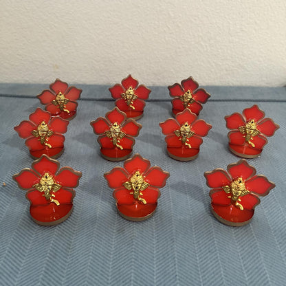 Set of ten red flower Ganesha car dashboard idols arranged in rows on a blue cloth