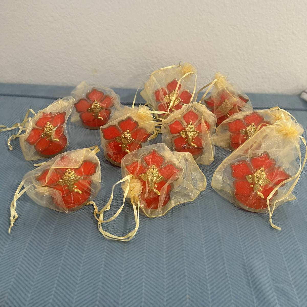 Ten Ganesha car idols each packed in a sheer gold drawstring potli bag for return gifts