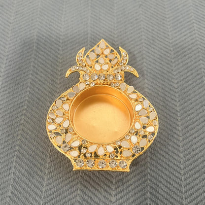 Single gold kalash-shaped tea light holder set with white mirrors, on a blue herringbone cloth
