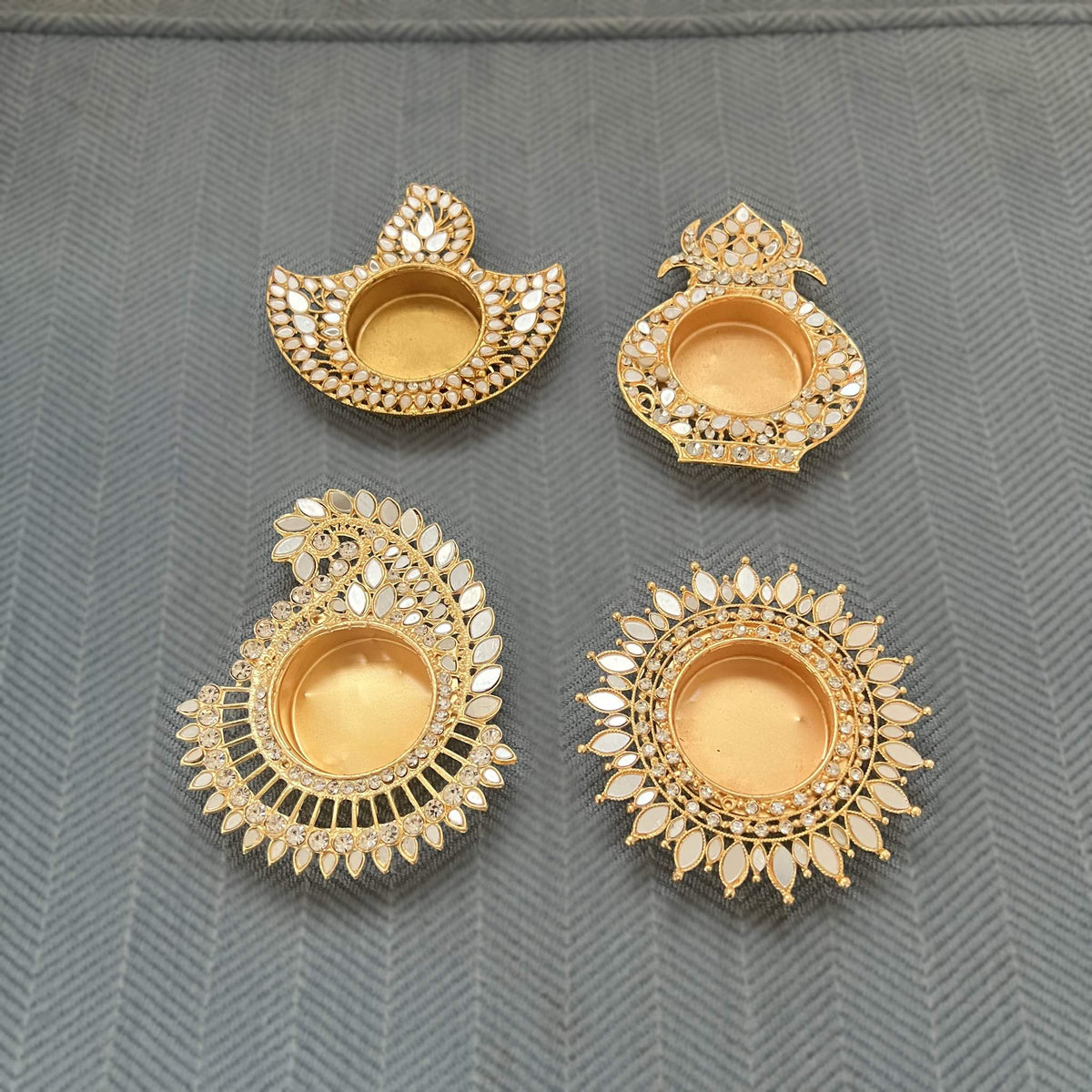 All four mirror diya designs side by side, unlit: deep, kalash, mango paisley and sunflower